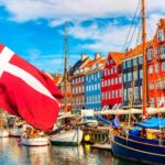 Political development: Picture of Danish flag in front of a number of boats in front of a number of brightly colored row houses