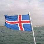 Political development: An image of a Iceland flag with the ocean behind it