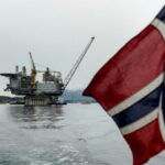 Political development: An image of a Norwegian flag in the foreground with an ocean oil platform in the background