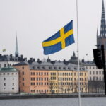 Political development: An image of the Swedish flag in front of a limestone coloured building
