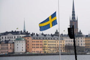 Political development: An image of the Swedish flag in front of a limestone coloured building